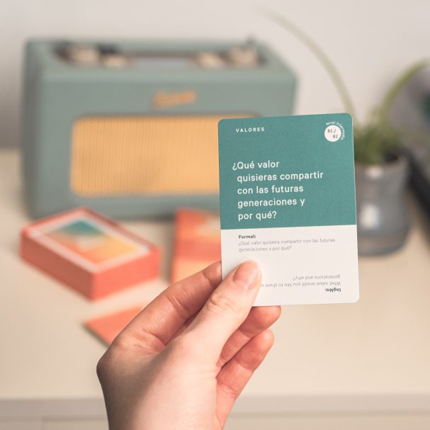 A person holding a card with a question, with a retro radio and potted plant in the background.